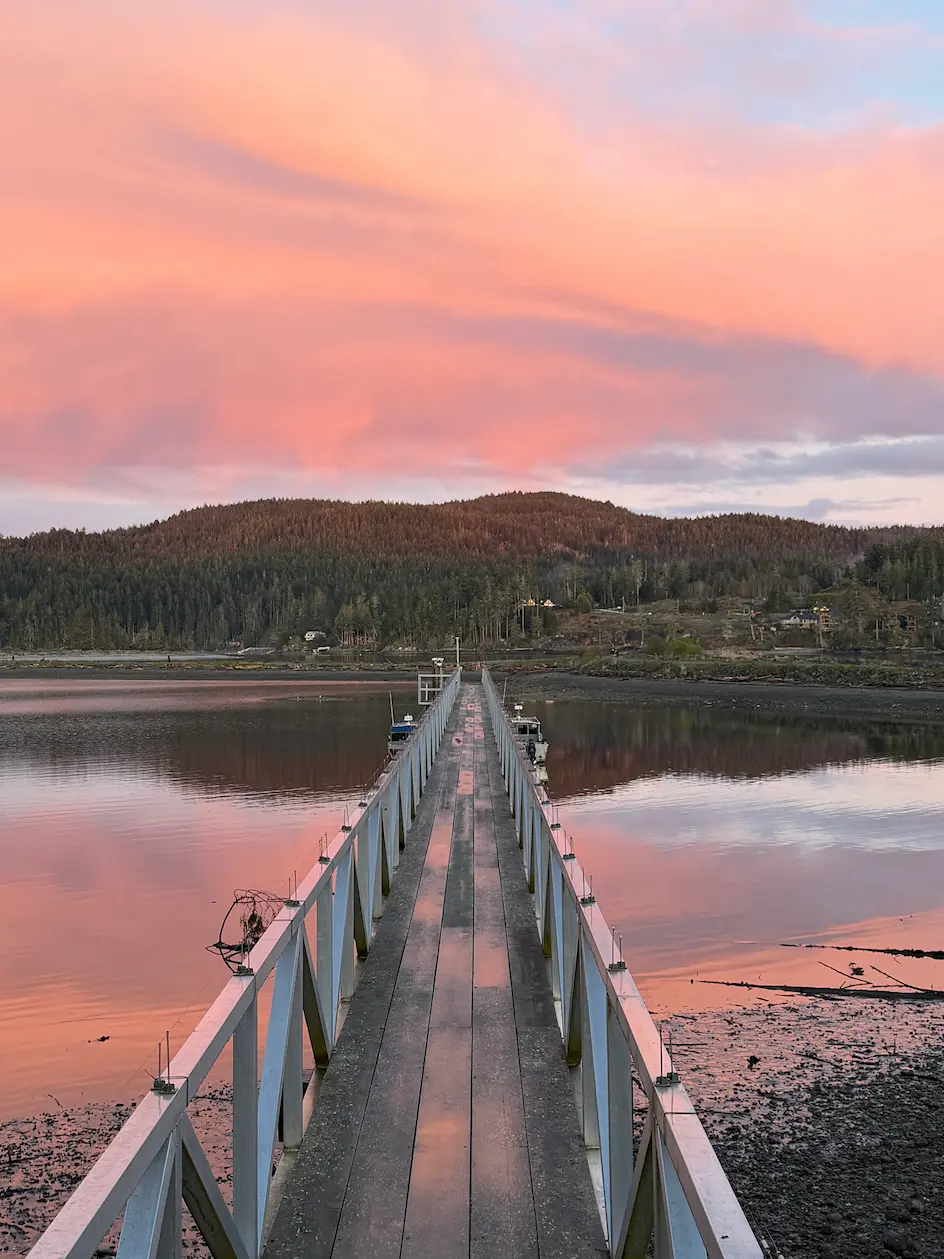 Wooden dock walkway over calm water at sunset