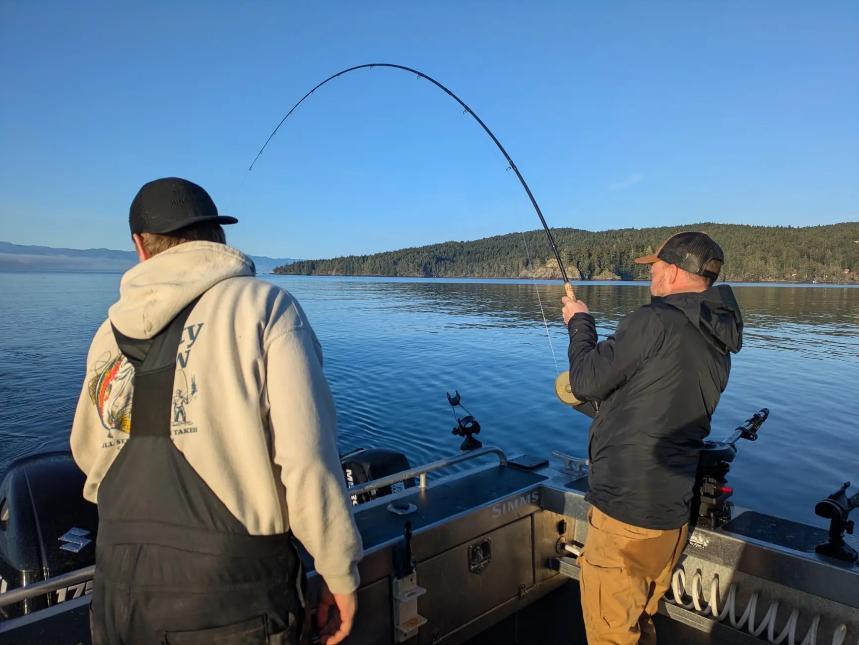 Angler fighting a winter Chinook salmon with a bent rod on the back deck of the 28ft Northwest