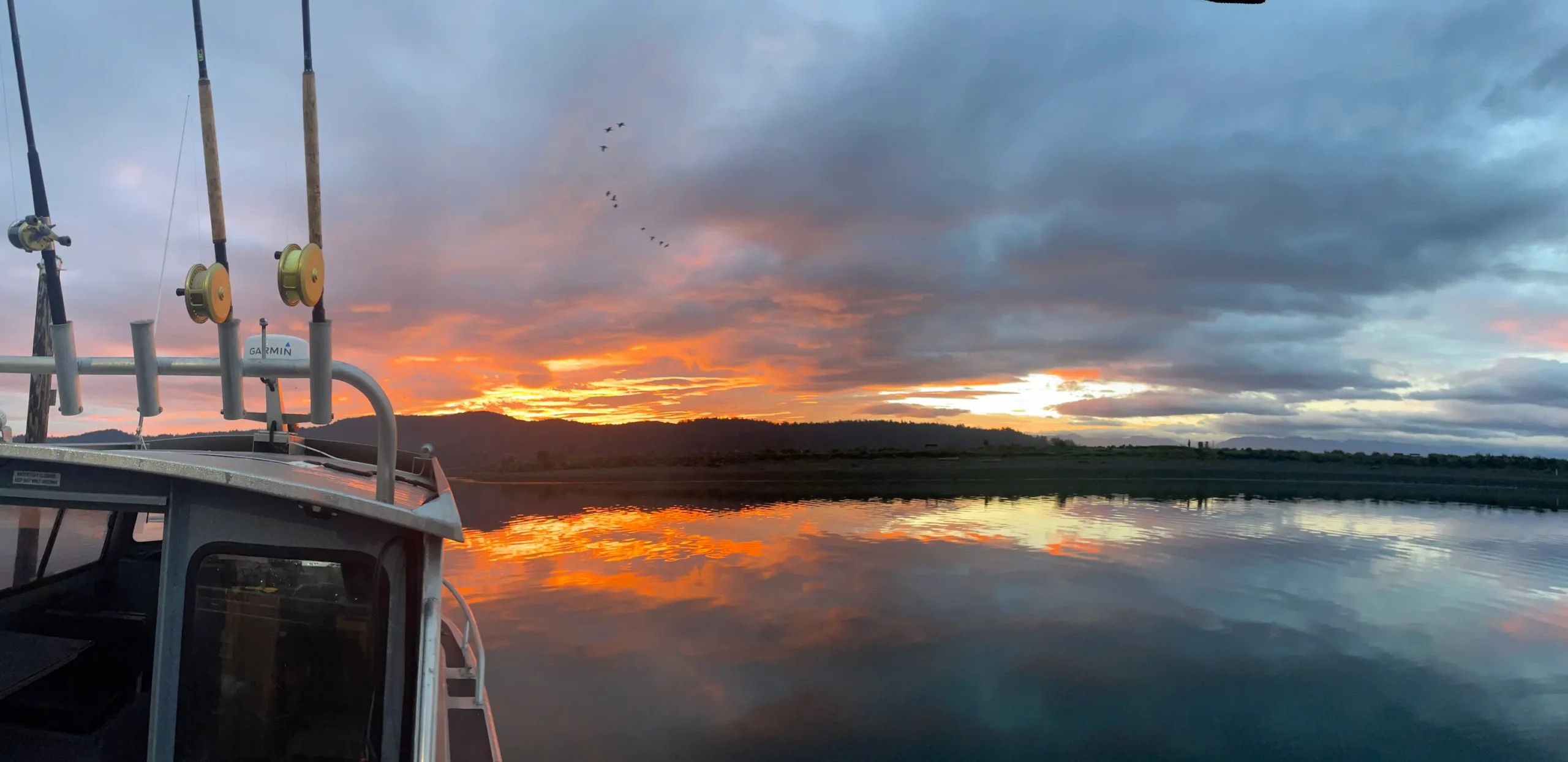 Sunrise view from the deck of the 28ft Northwest across calm water towards the Olympic Peninsula mountains